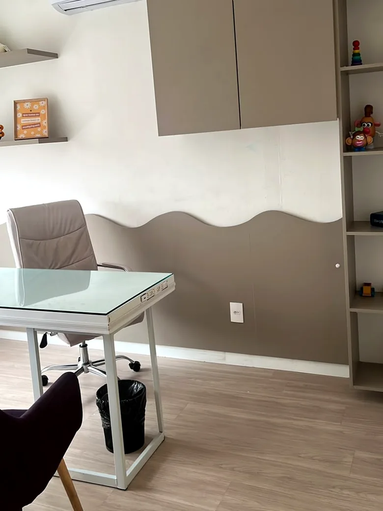 Consultório da Life Kids com parede em onda, estante de brinquedos pedagógicos e mesa de atendimento
