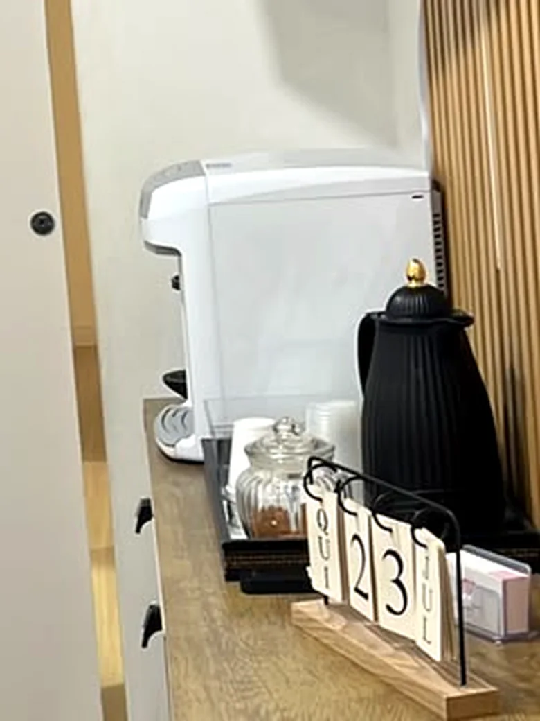 Aparador de madeira na recepção da Life Kids com máquina de café, garrafa térmica e calendário
